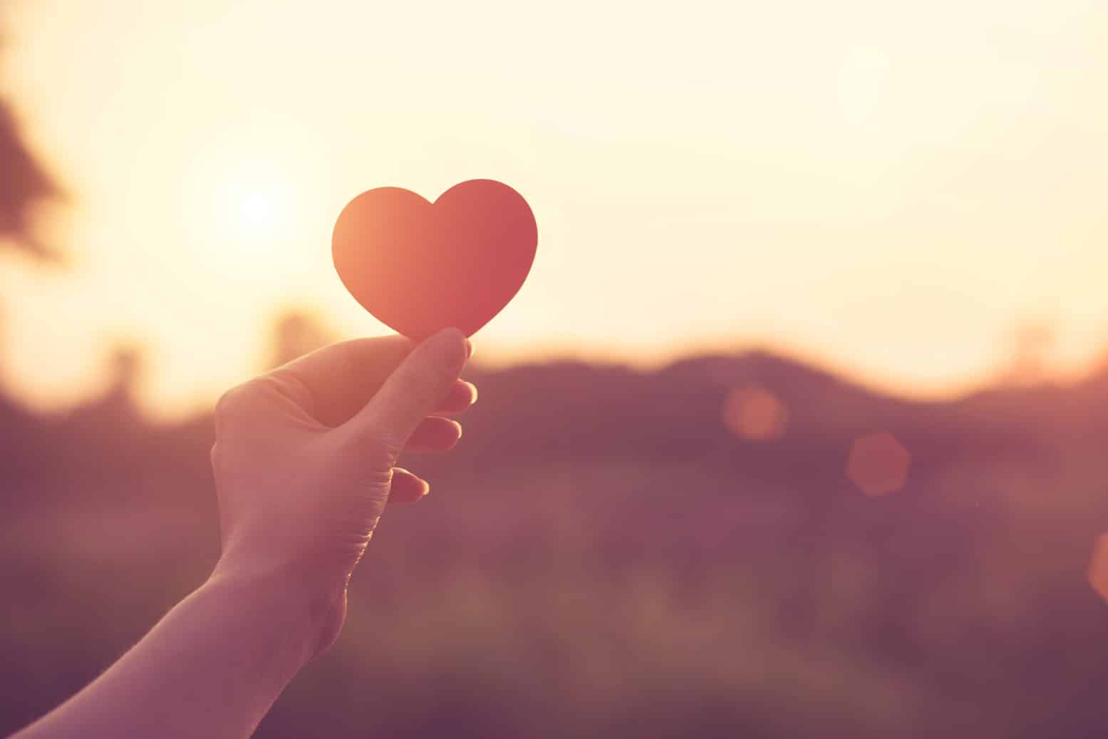 Hand holding heart shape in the sunset